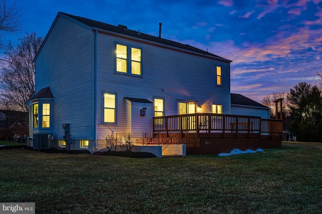 back house at dusk featuring a wooden deck, a yard, and central AC