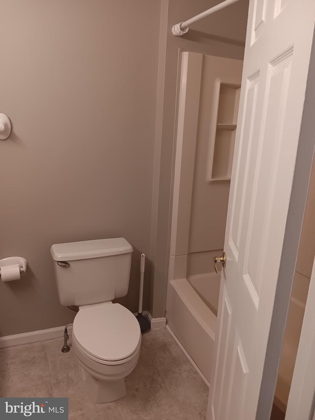 bathroom with tile patterned flooring, a tub, and toilet