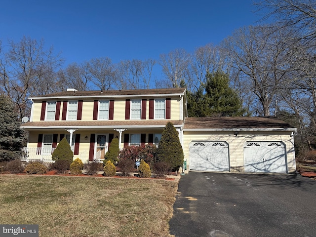 view of front of property featuring a garage, a porch, aphalt driveway, and a front yard