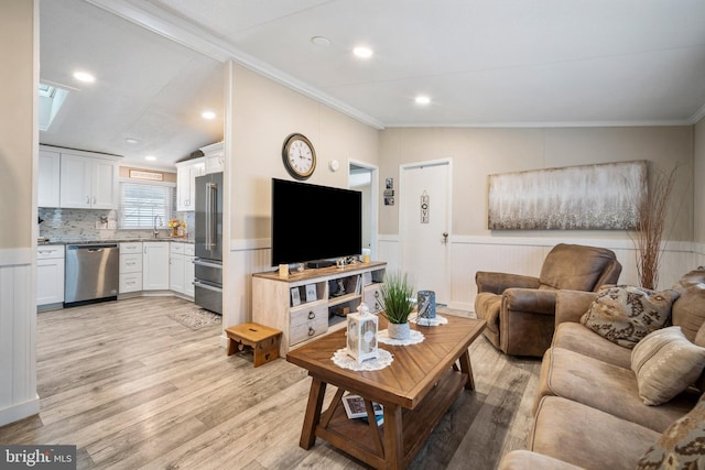 living room featuring light hardwood / wood-style flooring, sink, vaulted ceiling, and ornamental molding