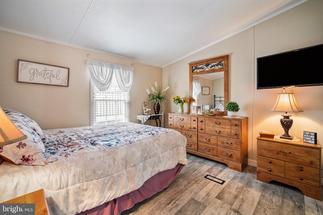 bedroom featuring vaulted ceiling, ornamental molding, and hardwood / wood-style floors