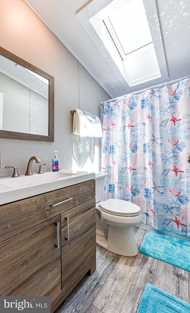 bathroom featuring toilet, lofted ceiling with skylight, a shower with curtain, vanity, and hardwood / wood-style floors