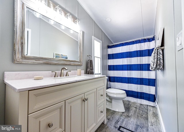 bathroom with hardwood / wood-style flooring, vanity, walk in shower, and toilet