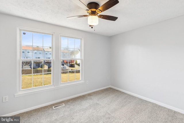 spare room with baseboards, visible vents, ceiling fan, a textured ceiling, and carpet flooring