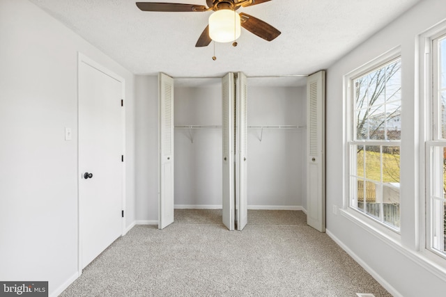 unfurnished bedroom with a textured ceiling, a ceiling fan, baseboards, carpet, and two closets