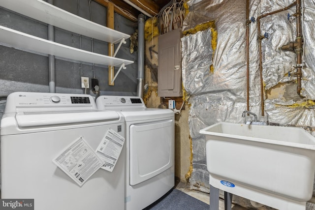 clothes washing area featuring a sink, laundry area, electric panel, and washer and dryer