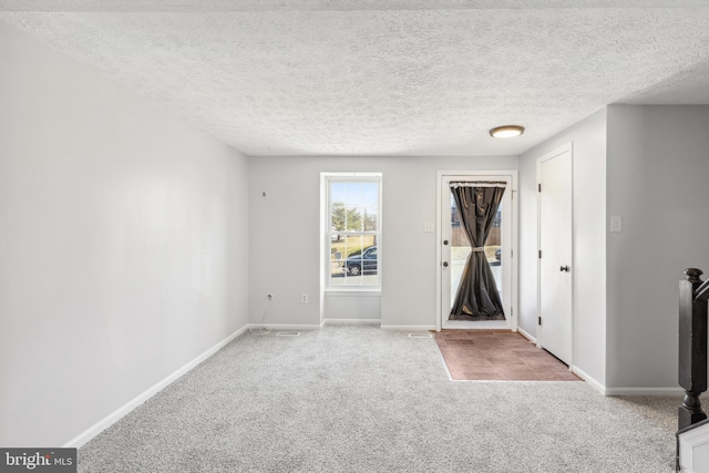 interior space with a textured ceiling, baseboards, and carpet flooring