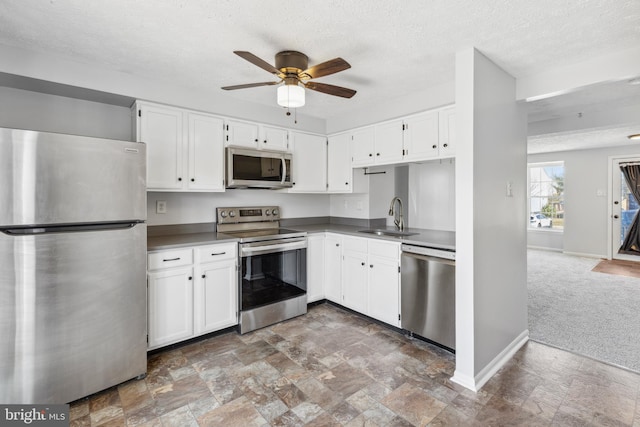 kitchen with stainless steel appliances, white cabinetry, a sink, and baseboards