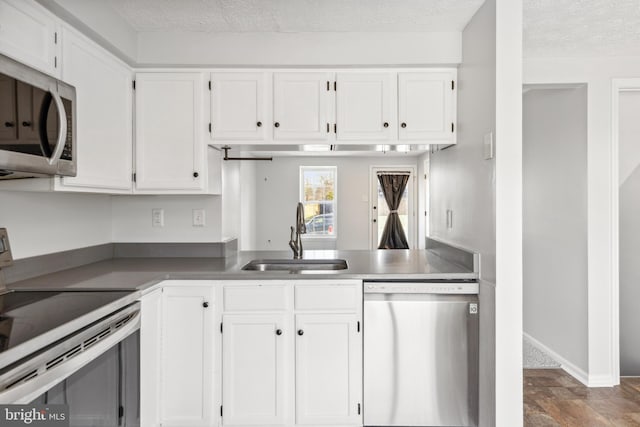 kitchen with stainless steel appliances, white cabinets, a sink, and a textured ceiling