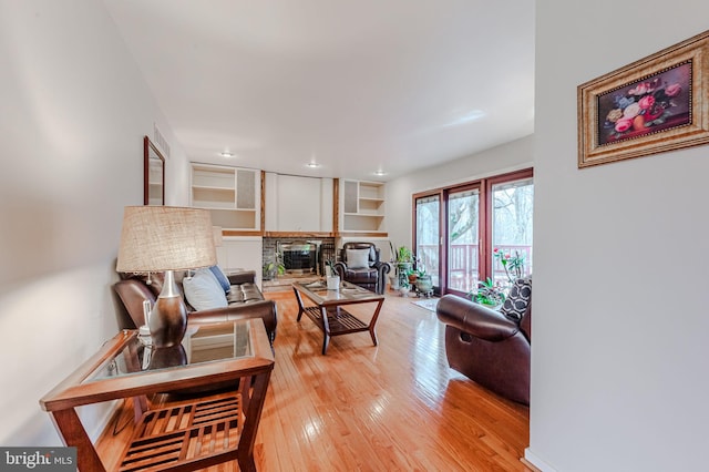 living room with a stone fireplace and light wood-type flooring