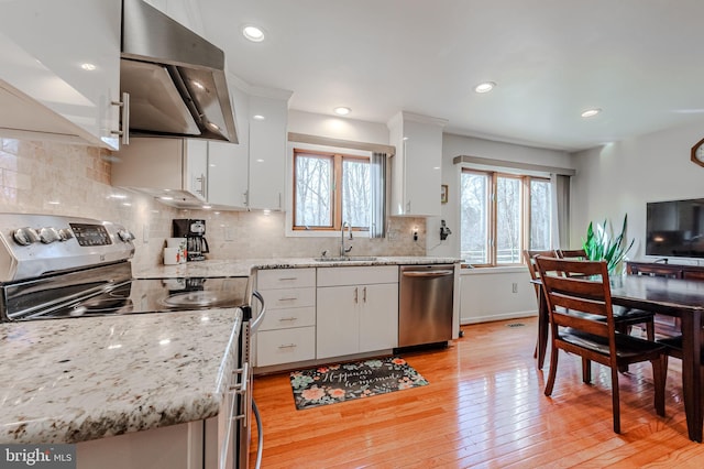 kitchen featuring sink, stainless steel appliances, ventilation hood, light stone countertops, and white cabinets