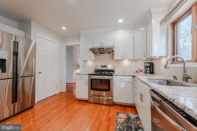 kitchen with sink, light hardwood / wood-style flooring, stainless steel appliances, light stone countertops, and white cabinets