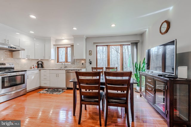 interior space with sink, appliances with stainless steel finishes, backsplash, light hardwood / wood-style floors, and white cabinets