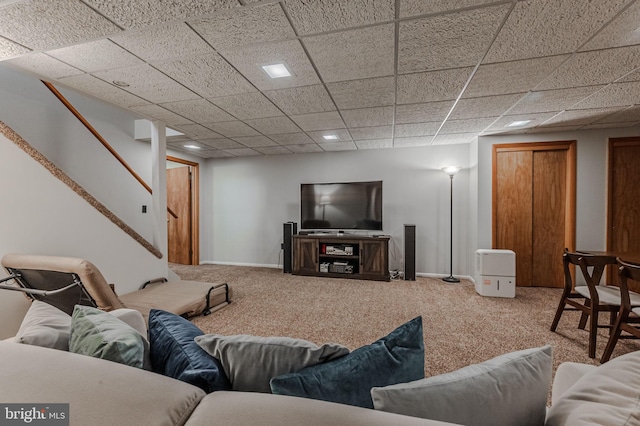 living room featuring carpet floors and a drop ceiling