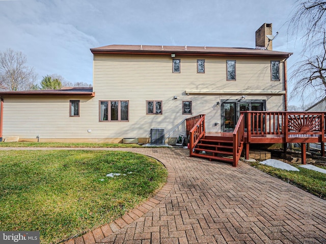 rear view of property with cooling unit, a wooden deck, a yard, and a patio area