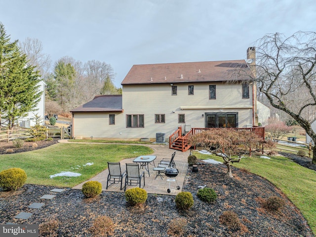 rear view of house with a wooden deck, a patio area, and a lawn