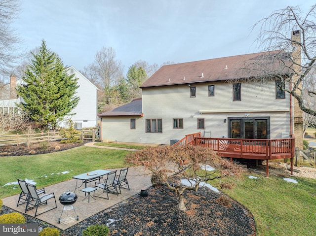 rear view of property featuring an outdoor fire pit, a deck, a patio area, and a lawn