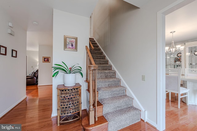 stairway featuring wood-type flooring and a chandelier