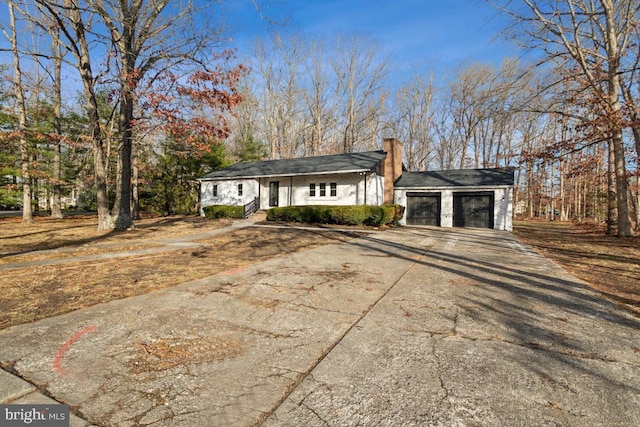 ranch-style house featuring a garage, driveway, and a chimney