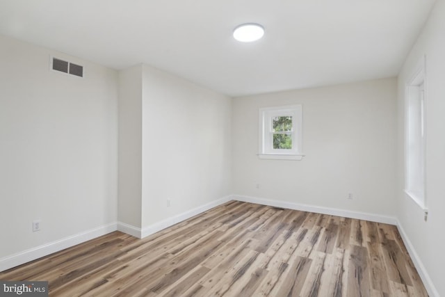 spare room featuring baseboards, visible vents, and wood finished floors