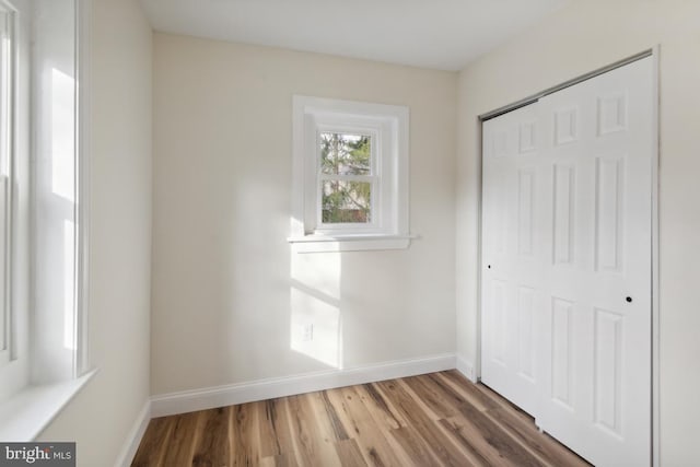 unfurnished bedroom featuring a closet, baseboards, and wood finished floors