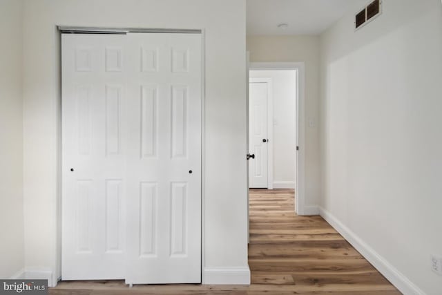 corridor featuring baseboards, visible vents, and wood finished floors