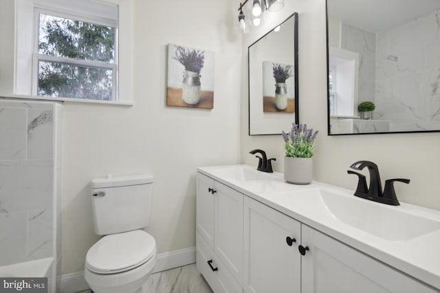 bathroom with marble finish floor, a sink, toilet, and baseboards