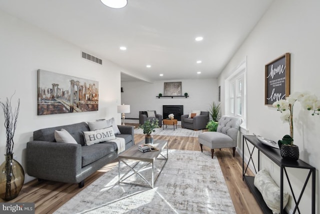 living area with a fireplace, visible vents, wood finished floors, and recessed lighting