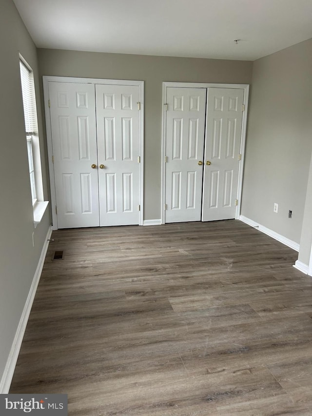 unfurnished bedroom featuring multiple closets and hardwood / wood-style flooring