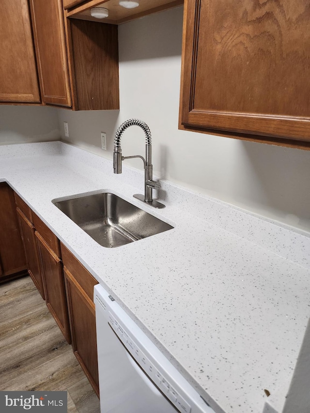 kitchen featuring light stone countertops, sink, white dishwasher, and light hardwood / wood-style flooring