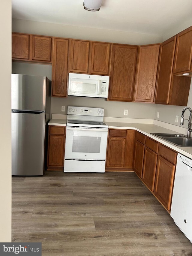 kitchen featuring sink, dark wood-type flooring, and white appliances