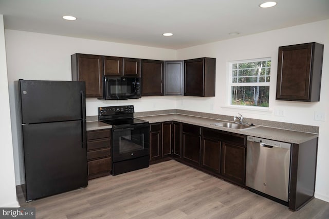 kitchen with dark brown cabinetry, sink, black appliances, and light hardwood / wood-style floors