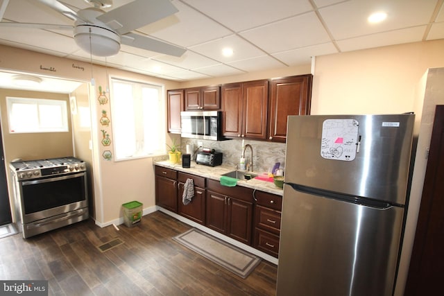 kitchen with sink, ceiling fan, stainless steel appliances, dark hardwood / wood-style floors, and tasteful backsplash