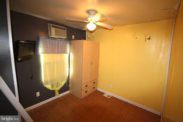 unfurnished bedroom with parquet floors, ceiling fan, and an AC wall unit