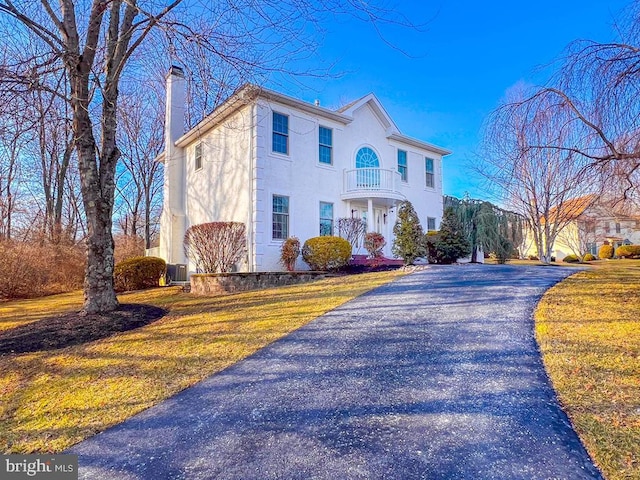 view of front of home featuring central AC, a front yard, and a balcony