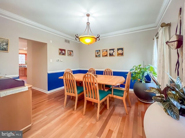 dining room featuring ornamental molding and light wood-type flooring