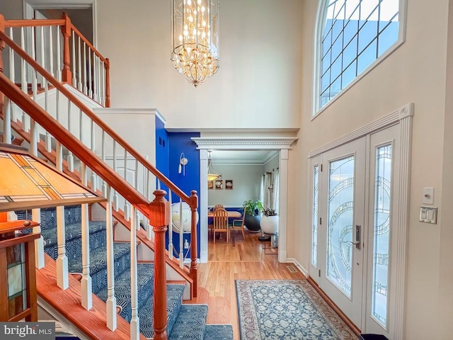 entrance foyer with a towering ceiling, light hardwood / wood-style flooring, and a chandelier