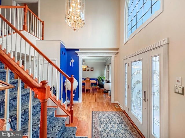 entrance foyer with an inviting chandelier, wood-type flooring, and a high ceiling