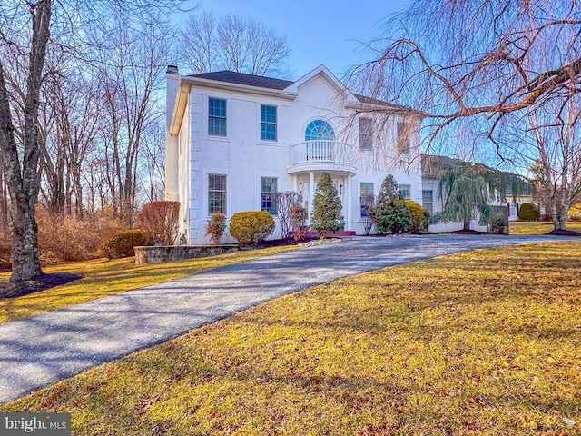 view of front of property featuring a balcony and a front lawn