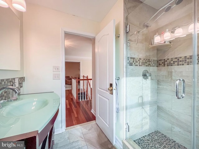 bathroom featuring vanity, an enclosed shower, and decorative backsplash