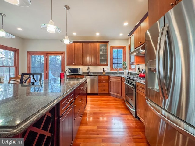 kitchen with a kitchen bar, sink, light hardwood / wood-style flooring, appliances with stainless steel finishes, and pendant lighting