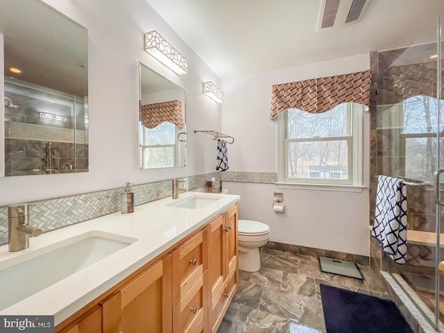 bathroom featuring vanity, plenty of natural light, a shower with door, and toilet