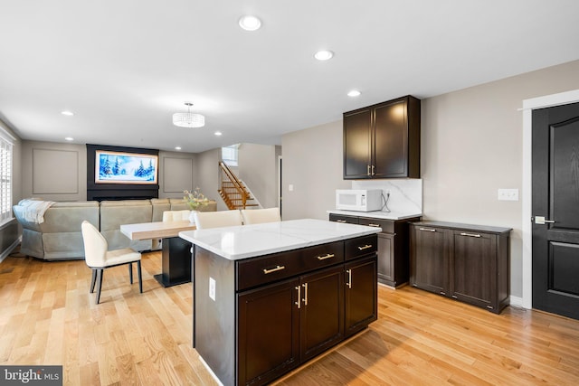 kitchen with a center island, dark brown cabinetry, and light hardwood / wood-style flooring