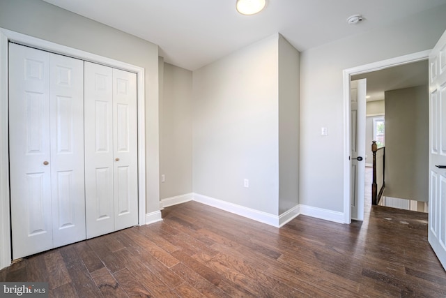 unfurnished bedroom with dark hardwood / wood-style floors and a closet