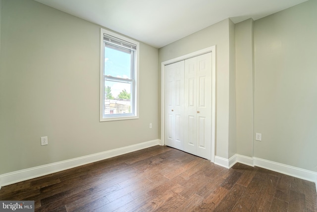 unfurnished bedroom with dark hardwood / wood-style floors and a closet