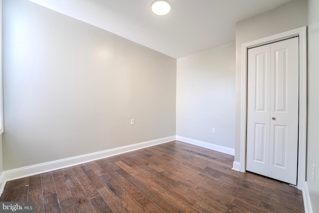 unfurnished bedroom with dark wood-type flooring and a closet