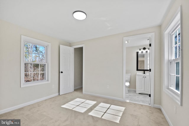 unfurnished bedroom with light carpet, sink, and ensuite bath