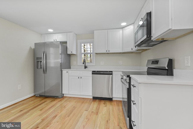 kitchen with stainless steel appliances, white cabinetry, sink, and light wood-type flooring