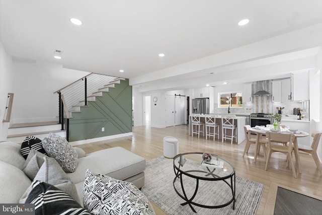 living room featuring baseboards, stairway, light wood-type flooring, and recessed lighting