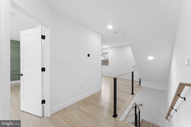 hallway with baseboards, recessed lighting, an upstairs landing, and light wood-style floors